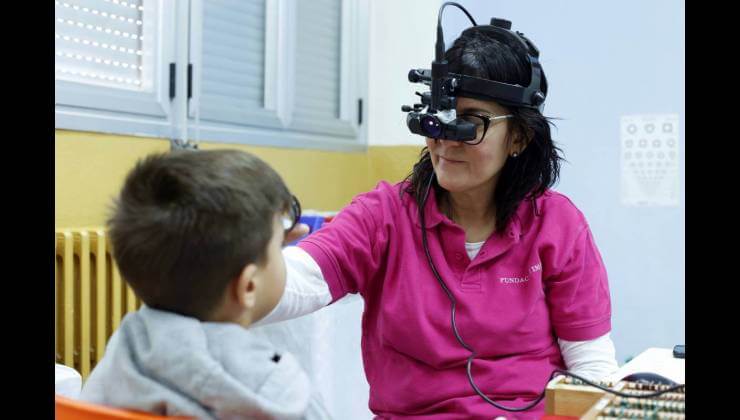 Doctora de oftalmología pediátrica evalúa la visión a un alumno.